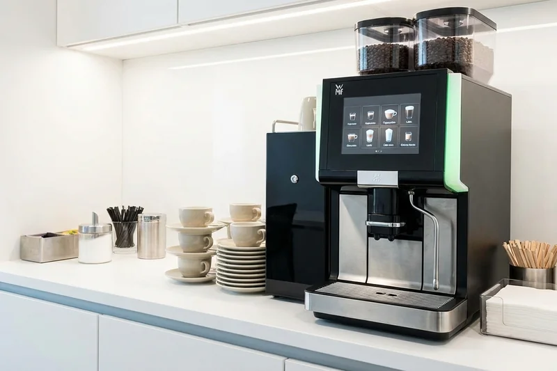 Mitarbeiter reinigt Kaffeemaschine selbst im Büro