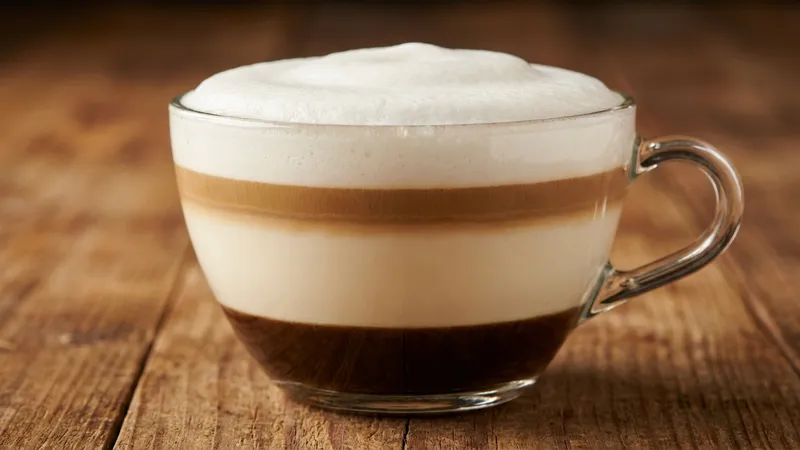Cappuccino im Glas mit sichtbaren Schichten und dicker Schaumkrone